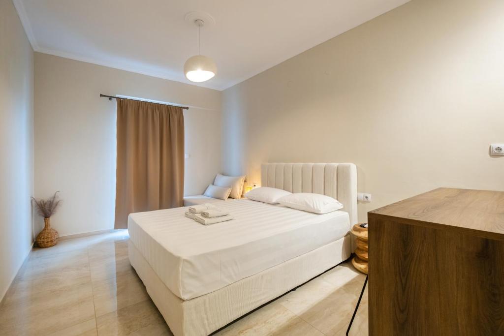 a white bedroom with a white bed and a window at Athena's Studios 2 in Polychrono