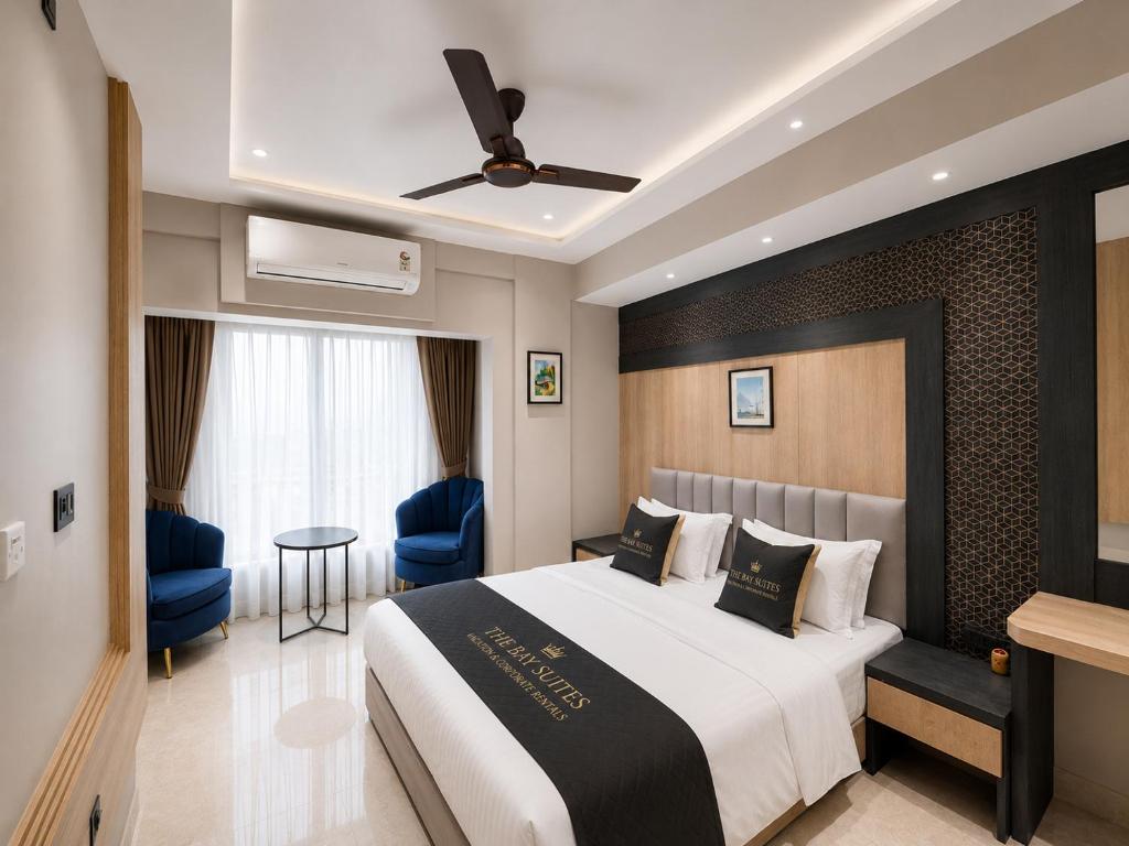 a bedroom with a large bed and blue chairs at The Bay Suites - NIS in kolkata