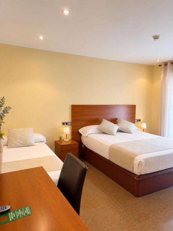 a hotel room with two beds and a table at Hostal La Tina in Port de la Selva
