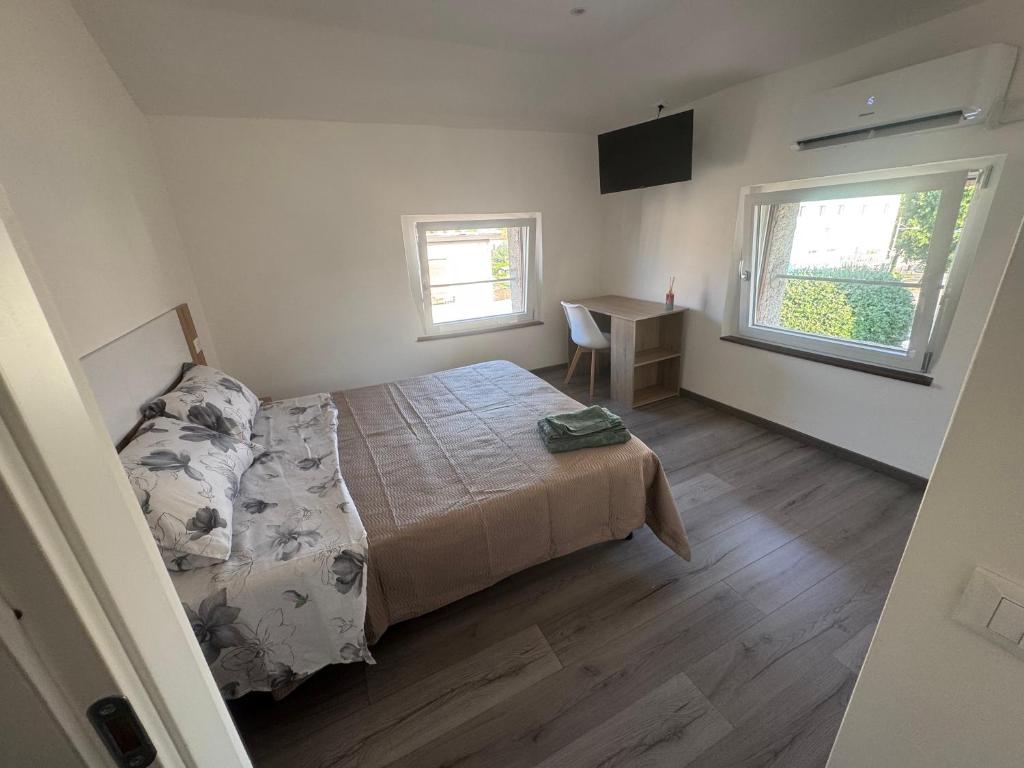 a bedroom with a bed and a desk and two windows at La maison Sophel in Pieris