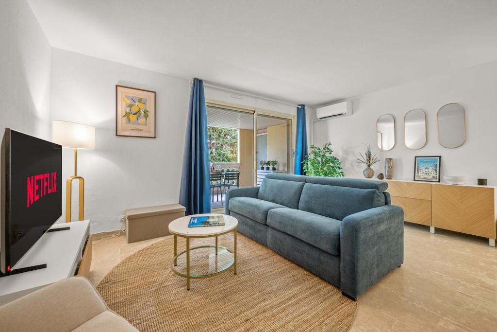 a living room with a blue couch and a tv at LE MARNI appartement central avec terrasse parking privé in Menton