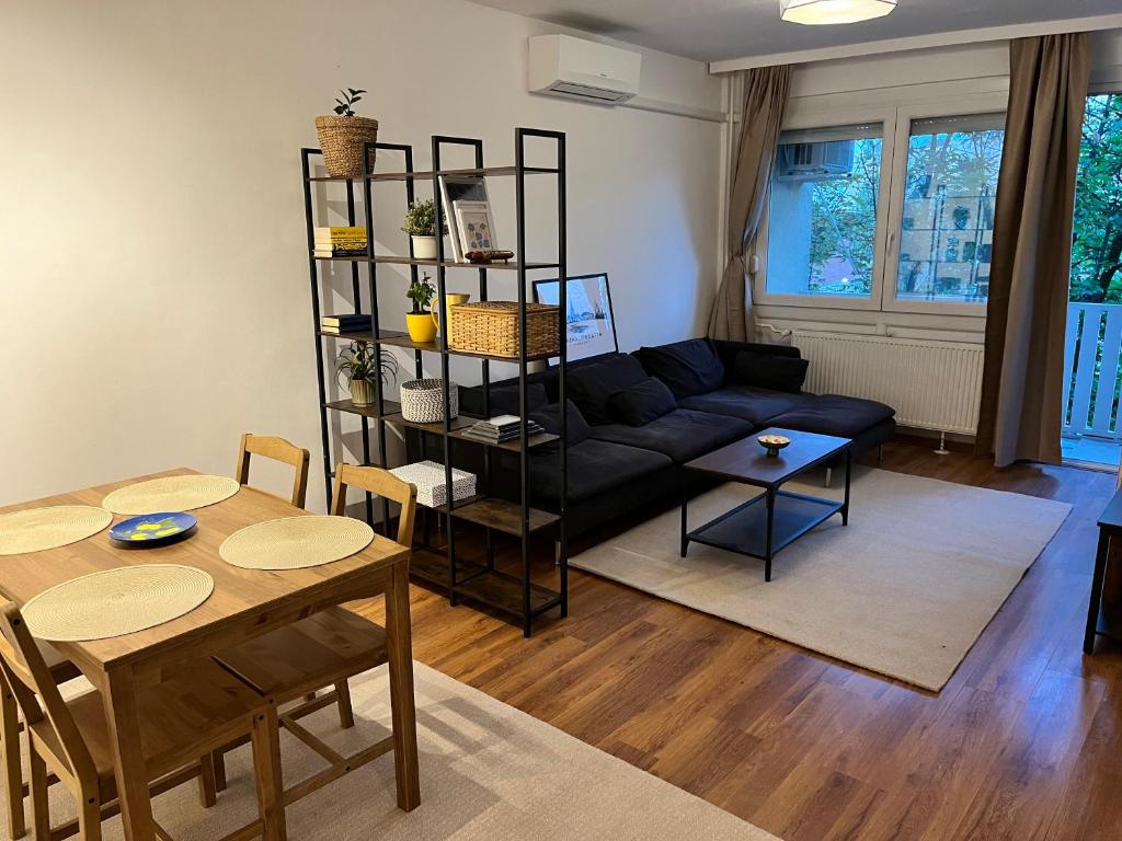 a living room with a black couch and a table at Battaville Apartment in Százhalombatta