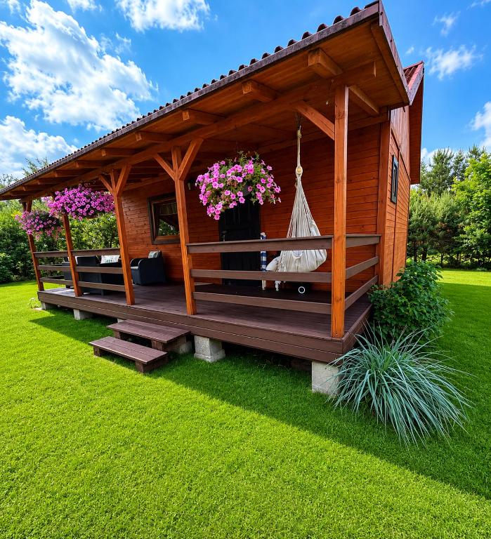 a wooden gazebo with a hammock in a yard at Letniskowy Domek Paullo in Słajszewo