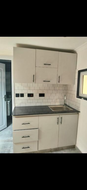 a kitchen with white cabinets and a sink at MPD Deluxe Suites in Kakamega