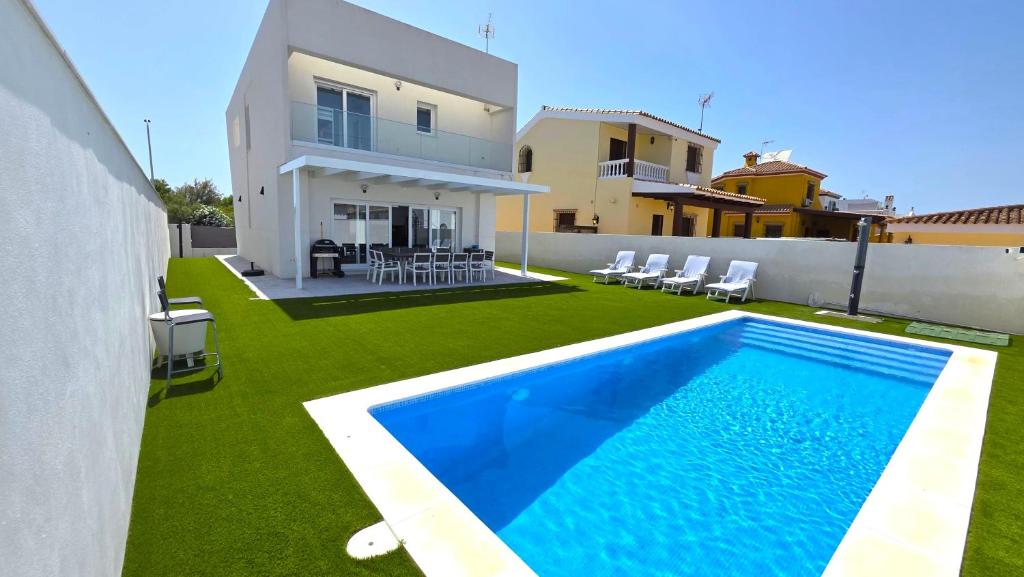 a backyard with a swimming pool and a house at Chalet Laguna Place in Chipiona
