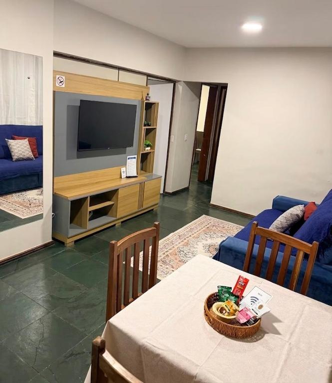 a living room with a table and a tv at Apartamento Prático Completo in Goiânia