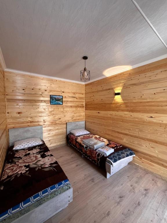 two beds in a room with wooden walls at Tamchy Residents in Tamchy
