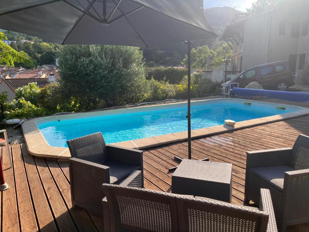 a swimming pool with an umbrella and chairs on a deck at Le Gîte Martin in Quillan