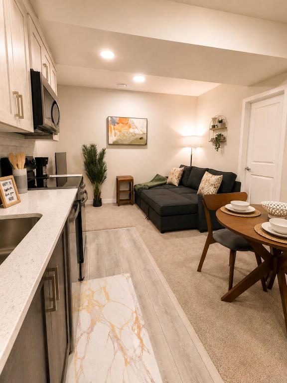 a kitchen and living room with a couch and a table at Cozy Private 1BR Basement Suite in Calgary