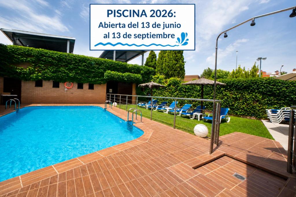 a swimming pool with a sign in front of a building at Hotel Reston Valdemoro in Valdemoro