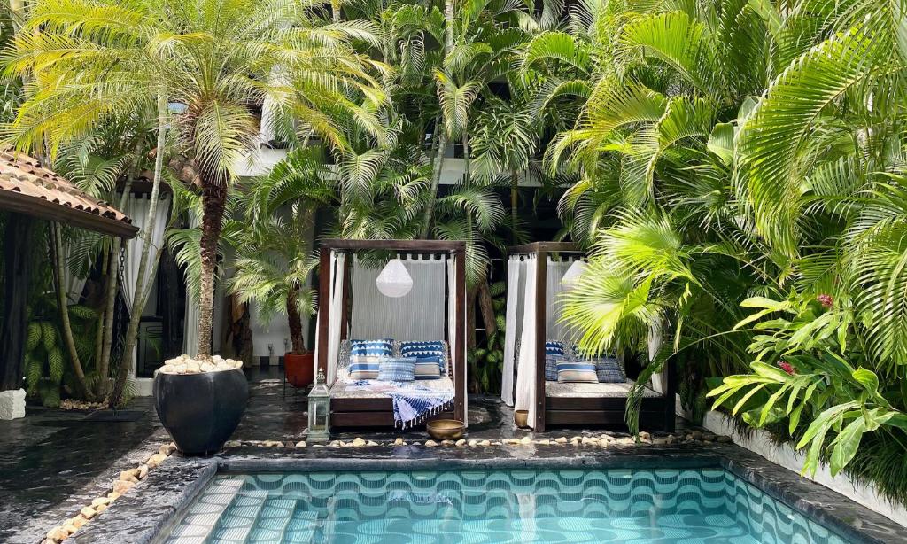 a swimming pool with two beds and palm trees at Tribal Hotel in Granada