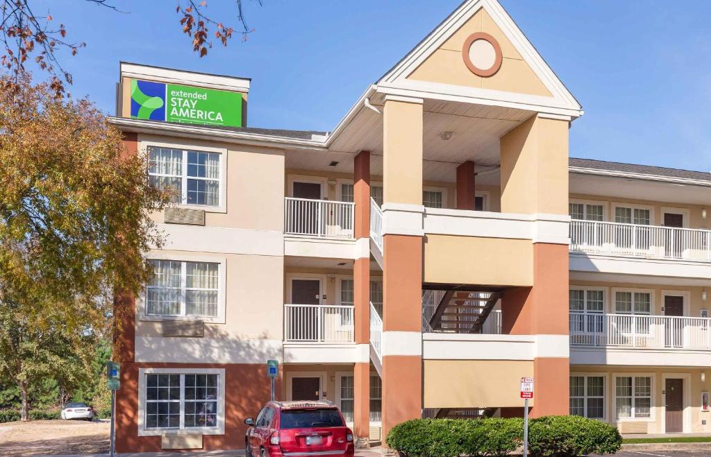 a building with a red car parked in front of it at Extended Stay America Select Suites - Raleigh - RDU Airport in Morrisville