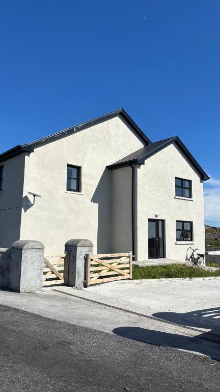a white house with a wooden fence in front of it at Dwellinghouse, Inishmore in Ourtnagapple
