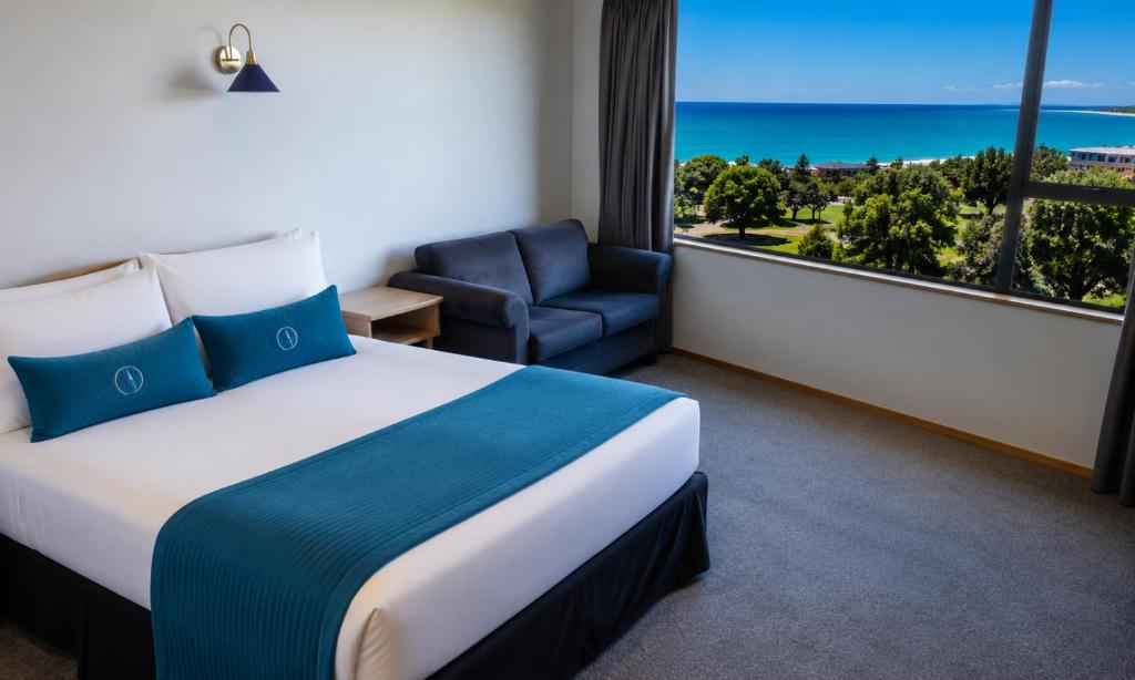 a hotel room with a bed and a chair and a window at Baywatch Motor Lodge in Timaru