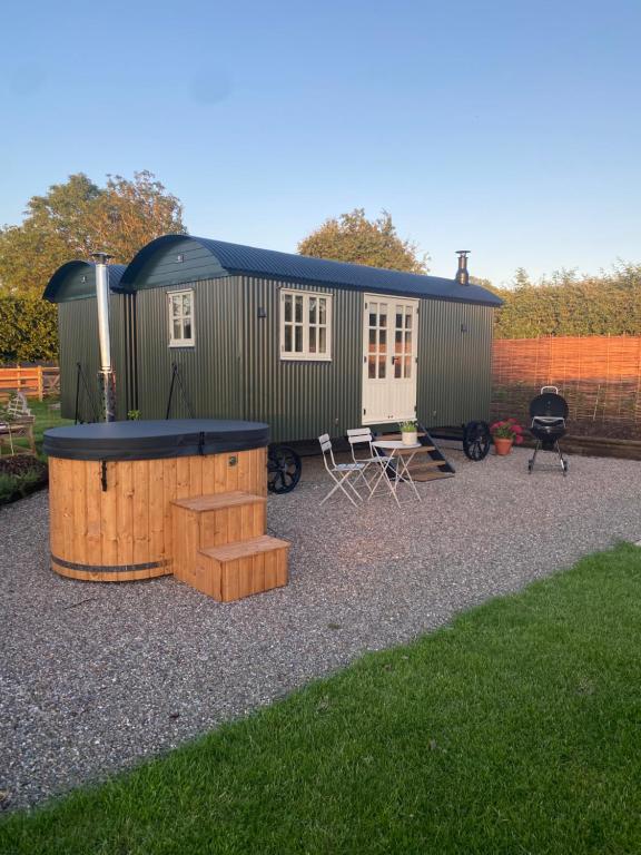 a green shipping container with a house in a yard at Hornbeam Holt in Broadway