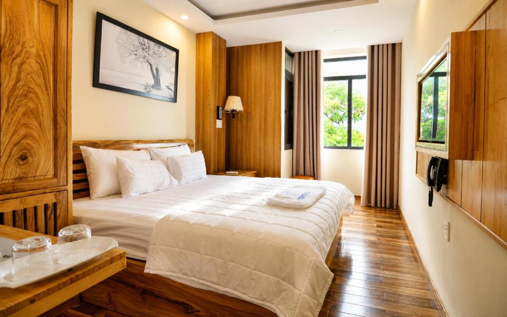 a hotel room with a large bed and a window at Senkotel Nha Trang Managed by NEST Group in Nha Trang