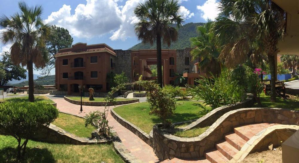 a house with palm trees in front of a building at Hotel Hacienda Cola del Caballo in Santiago