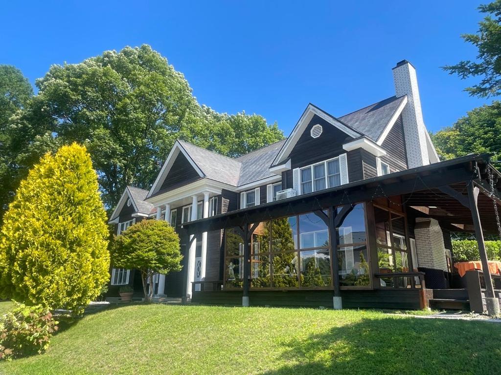 a house with a large porch on a lawn at Lodge Kent & Cottage Kent in Hokuto