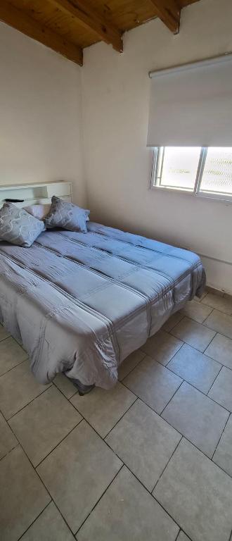 a large bed in a room with two windows at Depto El Mirador in Plaza Huincul