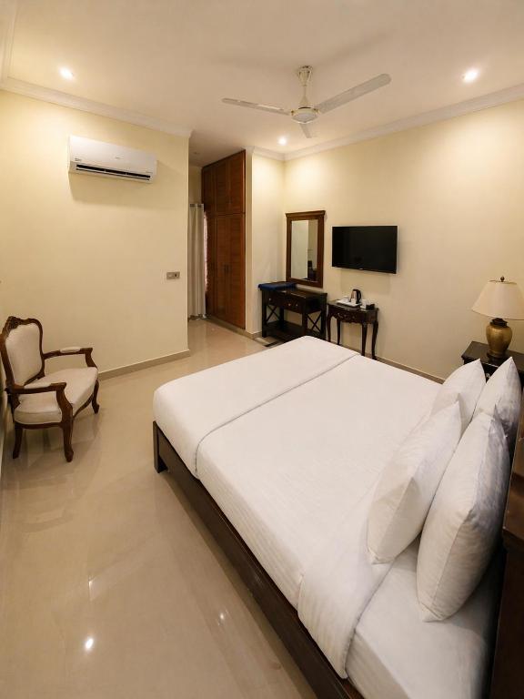 a bedroom with a large white bed and a television at The Corvane Residence in Islamabad
