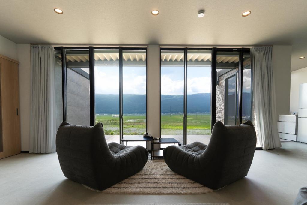 a living room with two chairs and a large window at AoAsoVilla in Aso