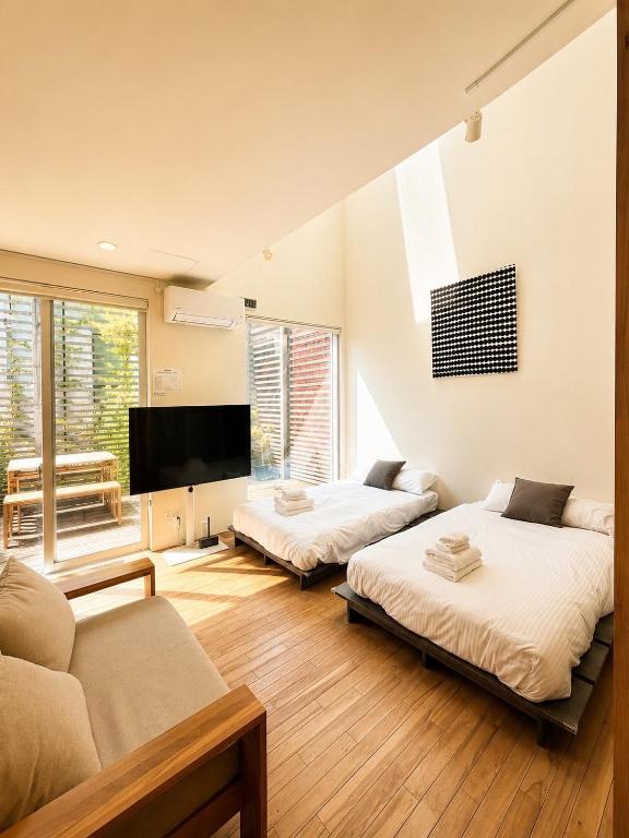 two beds in a room with a couch and a tv at Haus128 in Sapporo