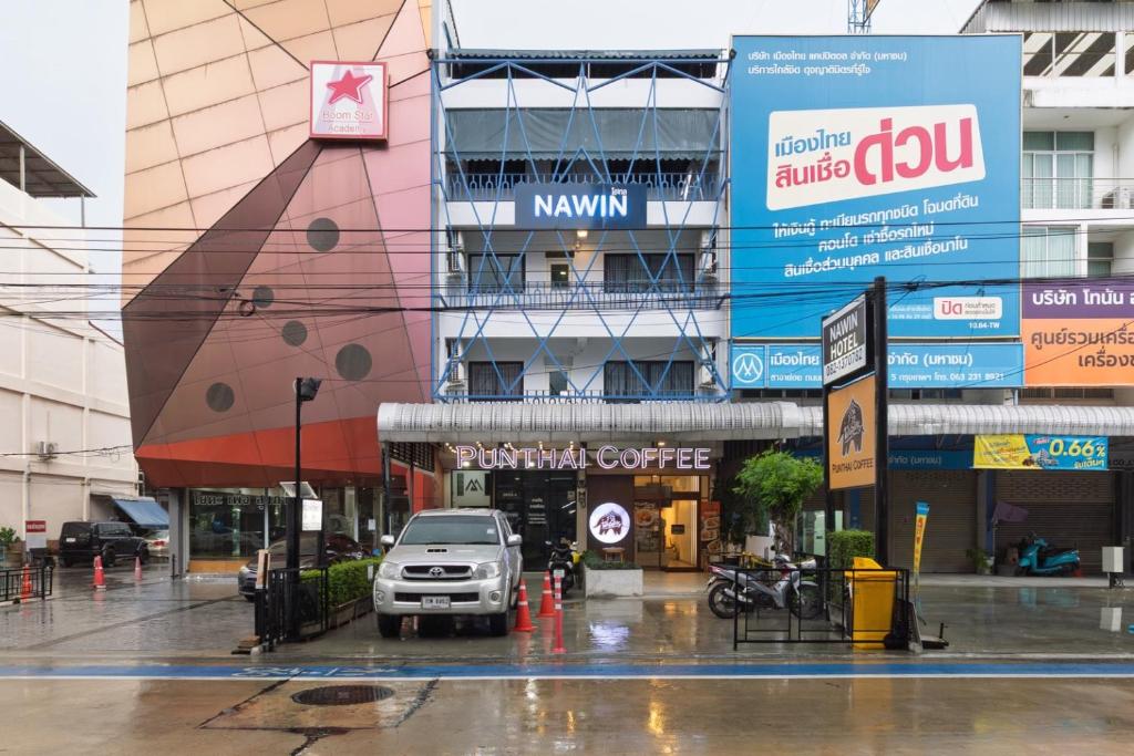 a car parked in front of a building in the rain at Nawin Hotel Donmueang in Thung Si Kan