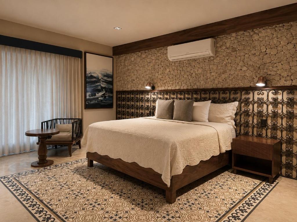 a bedroom with a large bed and a chair at Hotel Travertino in Mérida