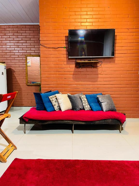 a couch sitting in front of a wall with a tv at Casa Vilarejo São Jorge in Sao Jorge
