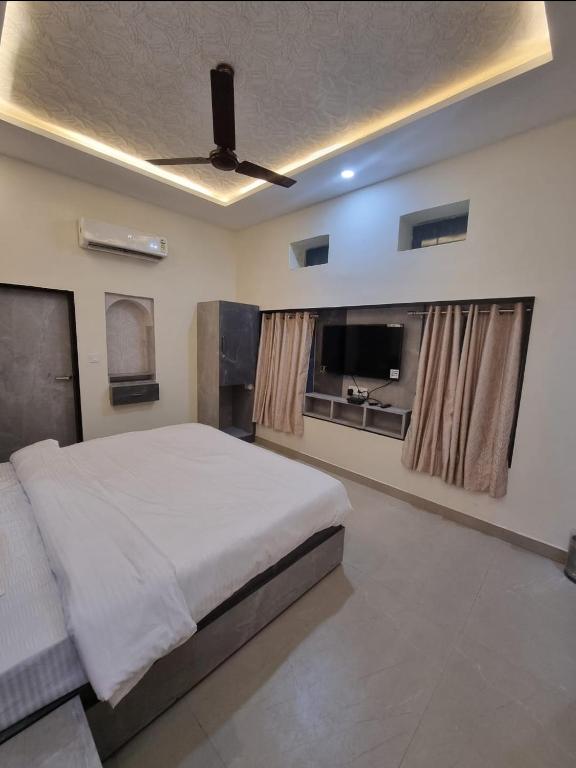 a bedroom with a bed and a ceiling fan at Green Villa - Luxury Rooms at peaceful location -200 mtrs away from Bus Stand -500 mtrs from Udaipur Railway Station - Family Suites w Kitchen also available in Udaipur