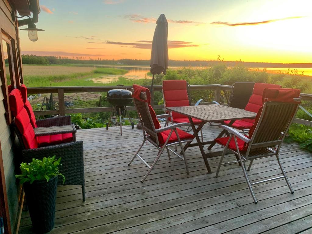a deck with a table and chairs and a sunset at Cottage with sauna and kayaks in Hammarland