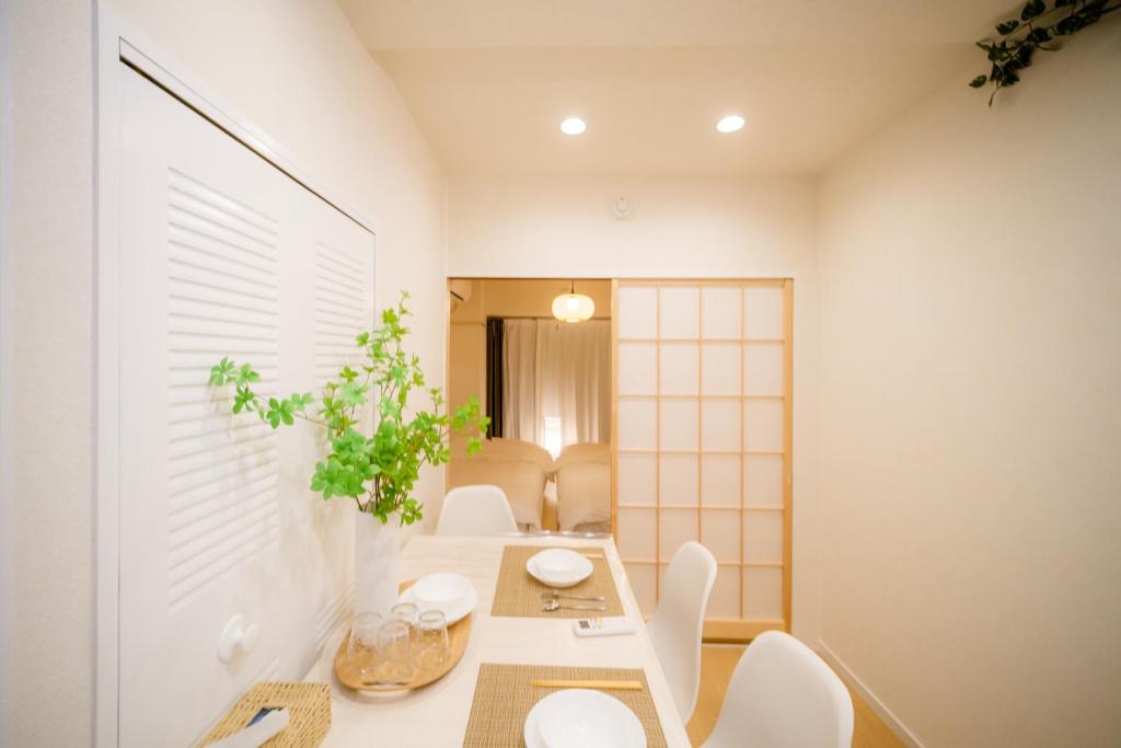 a dining room with a table and white chairs at HARERUYA Inn SHINJUKU in Tokyo