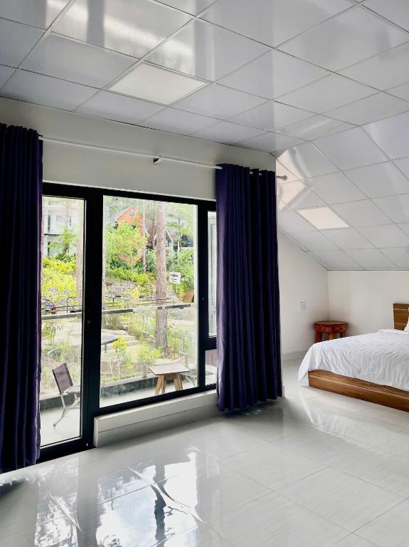 a bedroom with a bed and a large window at Mây Măng Đen Villa in Chương Nghĩa