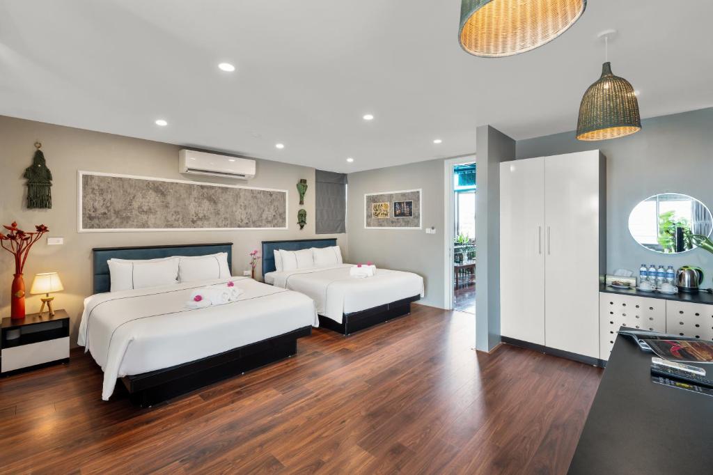 two beds in a room with wood floors at Valoria Legend Hanoi Hotel in Hanoi