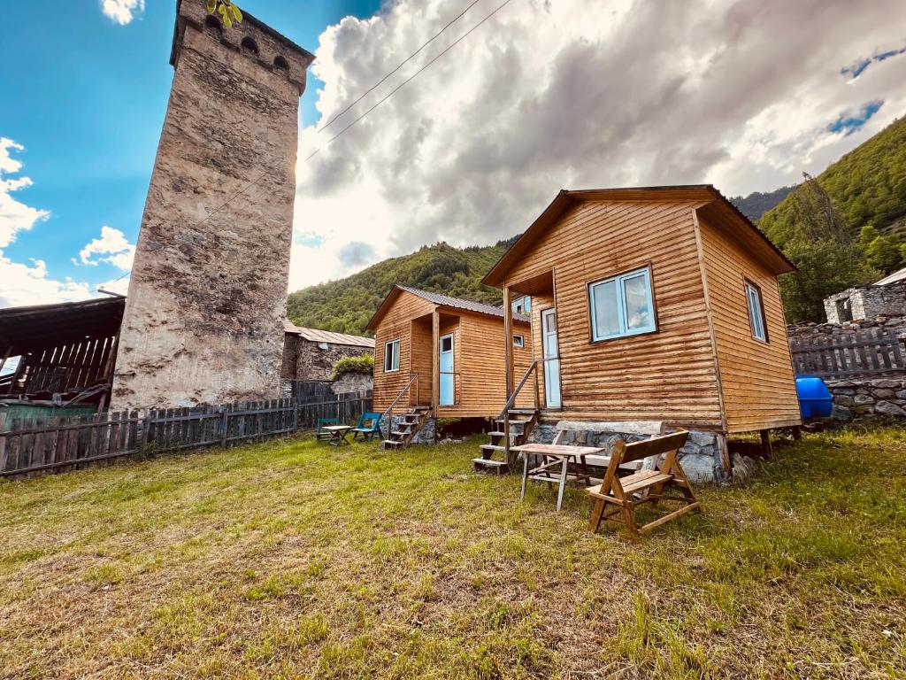 a small wooden house with a tower in a yard at SWEEPH in Mestia