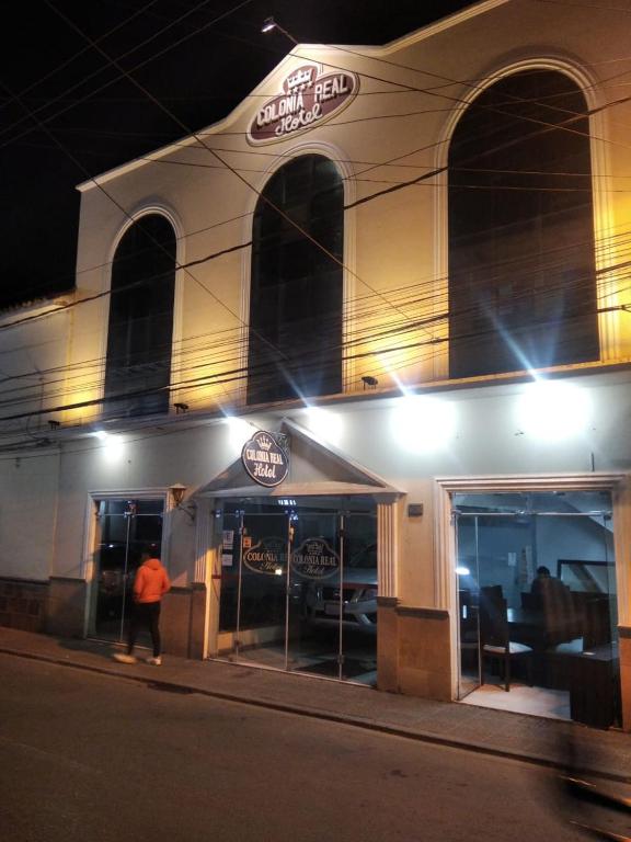 a man standing outside of a restaurant at night at Colonia Real in Sucre