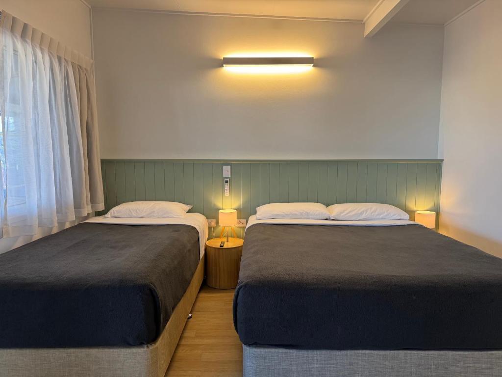 a room with two beds and a window at Pearly Shell Motel in Bowen