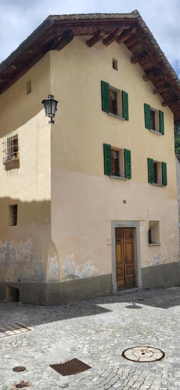 a large building with green shuttered windows and a door at Casa Silvia in Promontogno