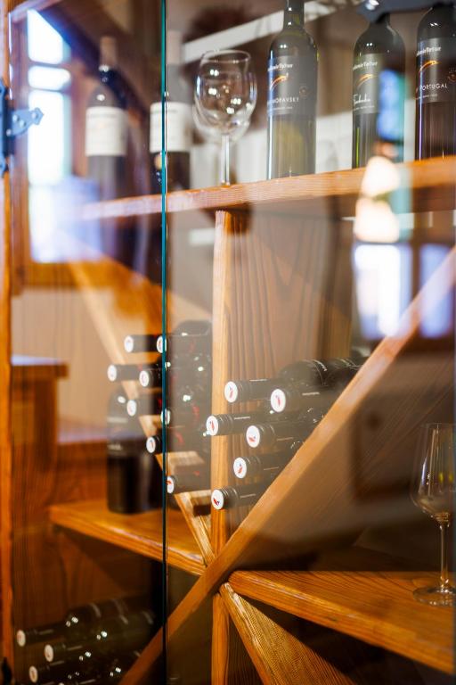 a glass shelf with wine bottles and wine glasses at Chalupa Vysoký Potok in Malá Morava