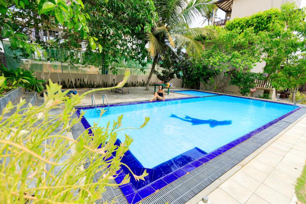 a person swimming in a large blue swimming pool at Soulinn Regina Weligama in Weligama