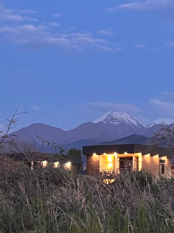 a house in a field with a snow covered mountain in the background at Marjan bay in Tossor