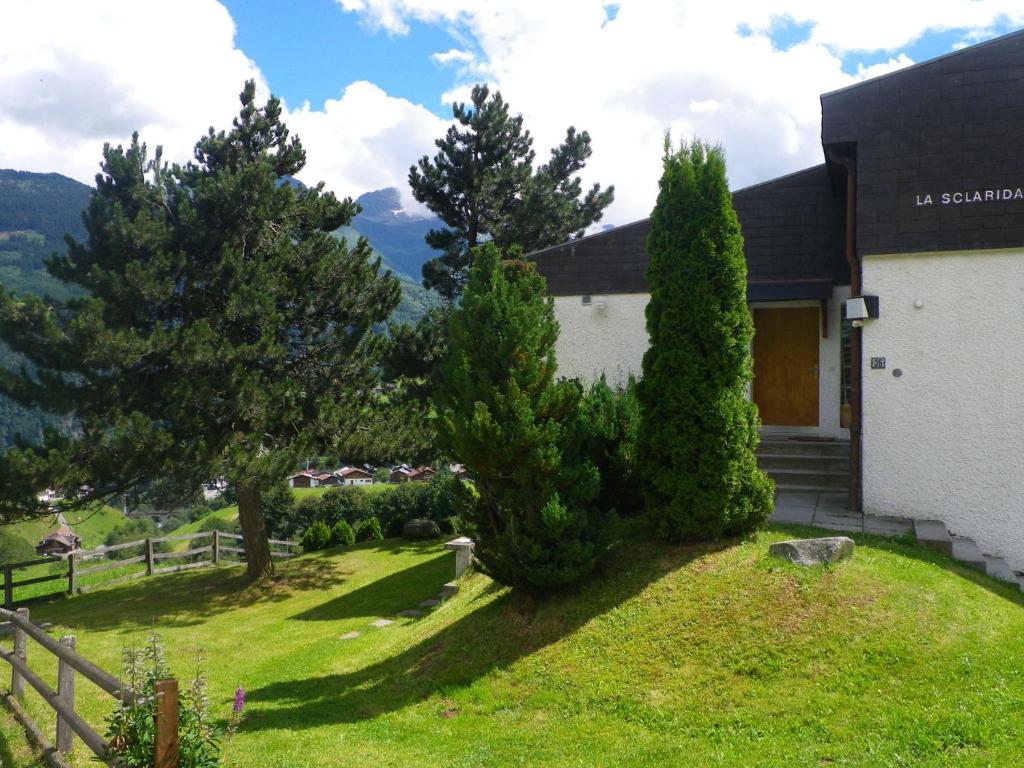 ein Haus mit Bäumen vor einem Hof in der Unterkunft Apartment in Disentis with Garden BBQ Views in Disentis