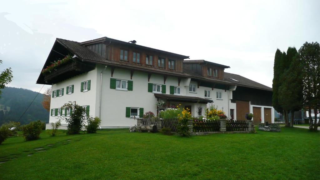 una grande casa bianca con un cortile verde di Ferienhof Schugg a Missen-Wilhams