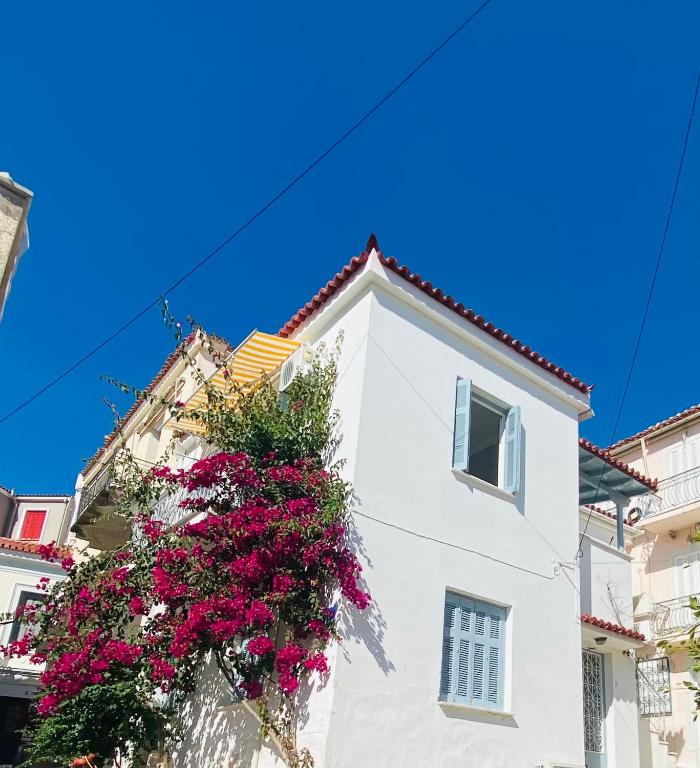 a white building with flowers on the side of it at Island Traditional House in Poros