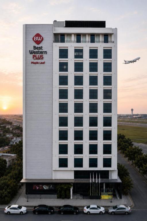an airplane is flying over a building with cars at Best Western Plus Maple Leaf in Dhaka