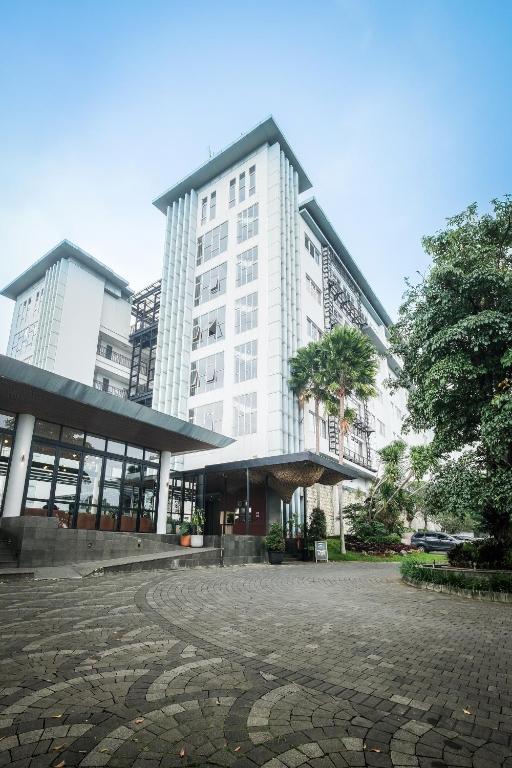 a large white building with a cobblestone courtyard in front of it at Clove Hotel Bandung in Bandung