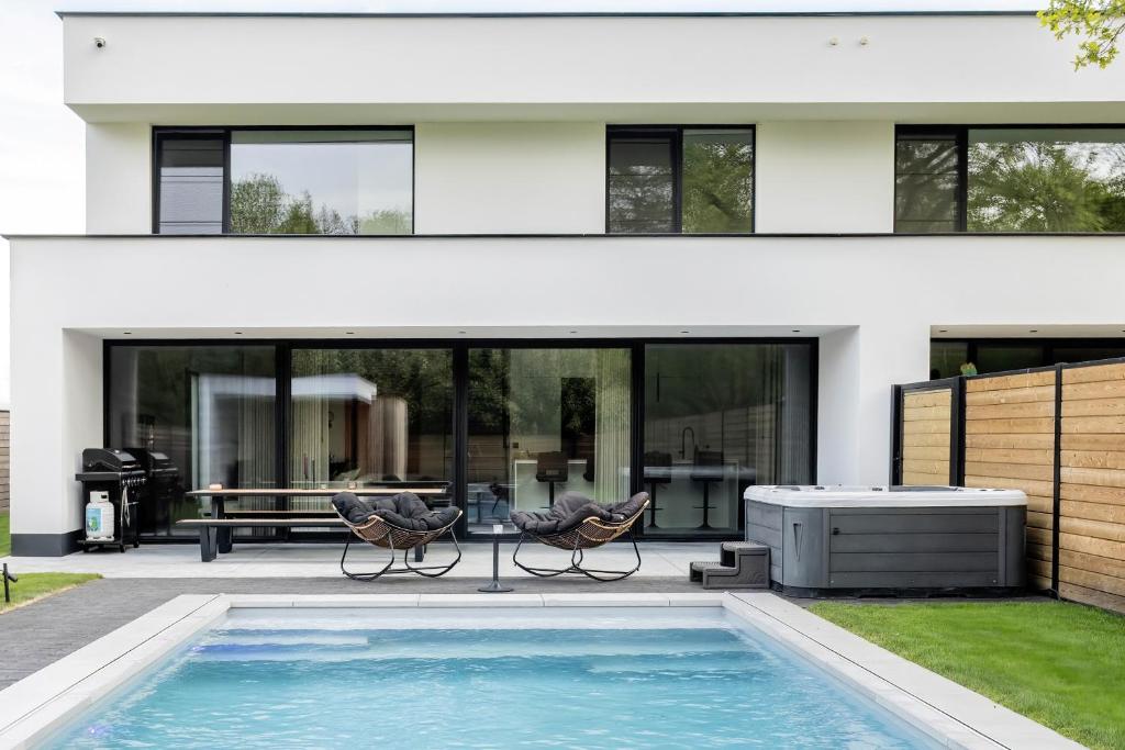 a house with a swimming pool and two chairs at Het Meer in Rotselaar