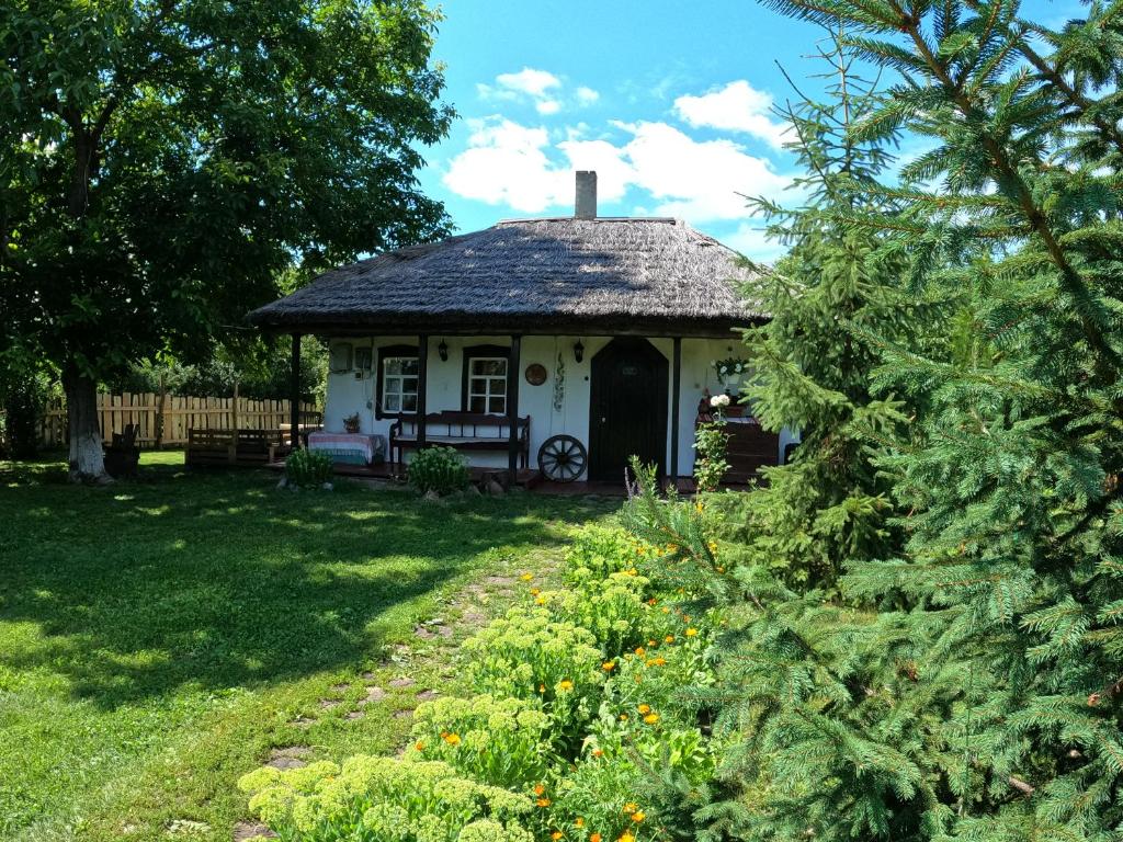 a small white house with a porch in a yard at Старий Хутір - Етно Хатина 1914 in Oposhnya
