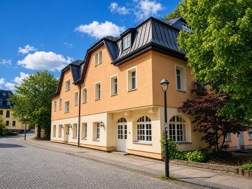 a large orange building with a black roof on a street at Hotel zum Felsenkeller Oybin in Oybin