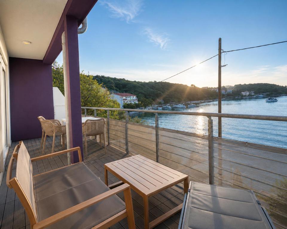 a balcony with a table and chairs and a view of a river at Aparthouse Penelope in Supetarska Draga